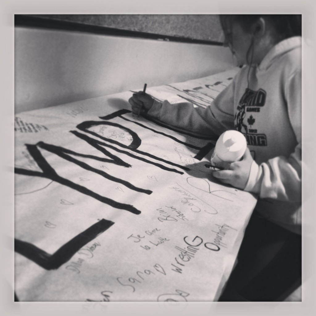 Taylor signing the "Support Olympic Wrestling" banner at the 2013 Renfrew Rumble.